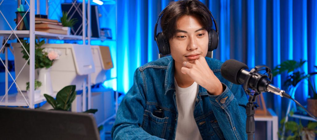 Podcaster con auriculares piensa frente al micrófono si el invitado que le proponen encaja en su pódcast