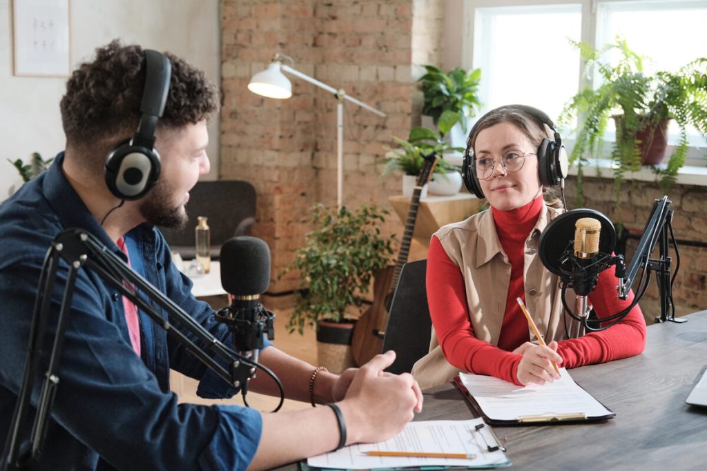 Presentador e invitada graban una entrevista de pódcast con micrófonos en un estudio